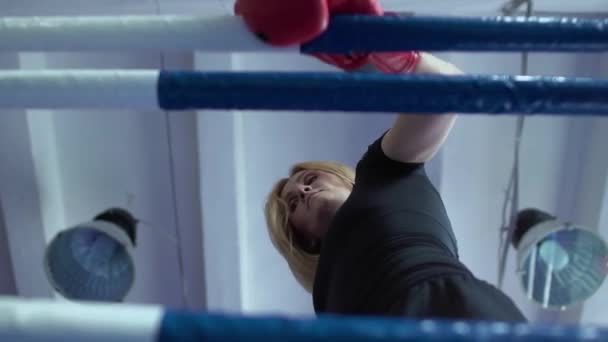 Женщина в боксёрских перчатках касается веревки и ходит по боксерскому рингу — стоковое видео