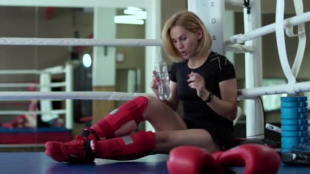 Mujer cansada sentarse en la esquina del ring de boxeo y beber agua — Vídeo de stock
