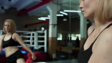 Spor salonunda vücudunu ayna önünde uzanan giyen güzel kadın