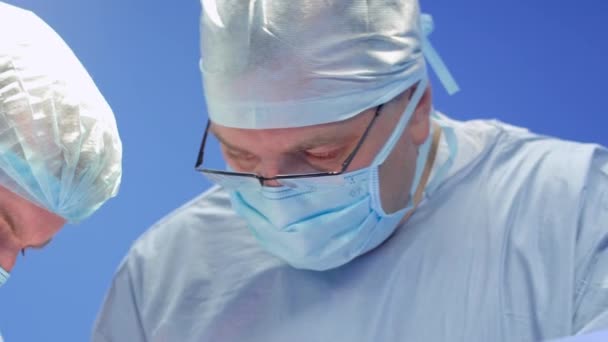 Два профессиональных хирурга во время операции — стоковое видео