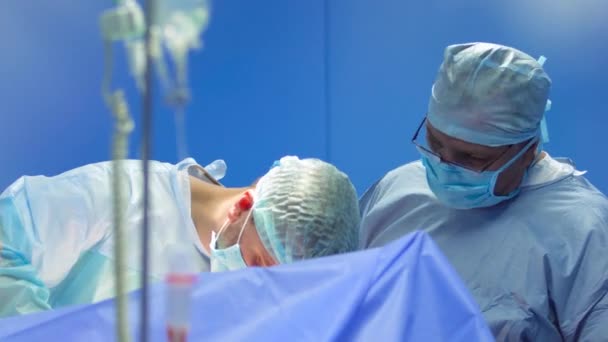 Cirurgiões em máscaras protetoras e uniformes fazem a operação — Vídeo de Stock