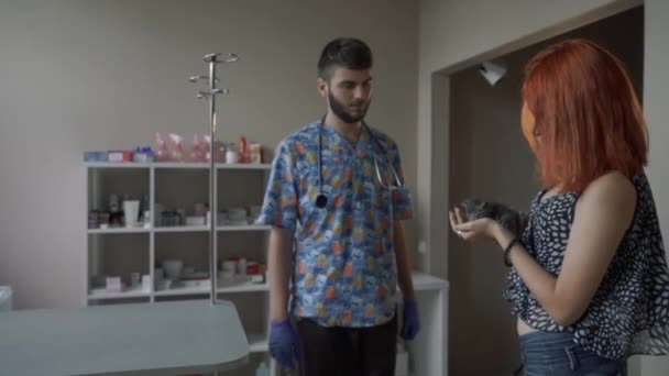 Rudowłosa dziewczyna w klinice weterynaryjnej posiada mały kotek w ramionach — Wideo stockowe