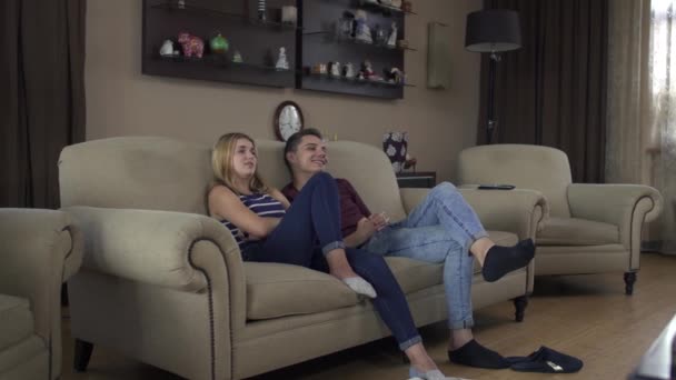 Красивая влюбленная пара дома на диване смотрит телевизор — стоковое видео