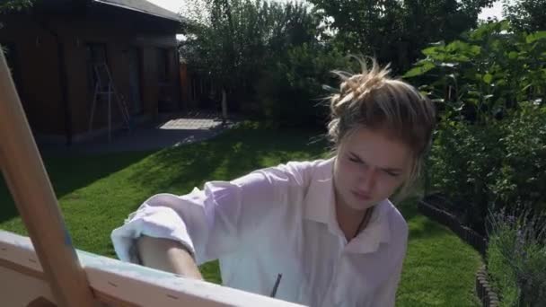 Menina jovem entusiasticamente desenha no quintal — Vídeo de Stock