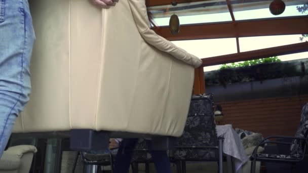 Cara com uma menina está carregando uma cadeira de couro — Vídeo de Stock