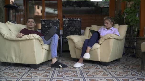 Jovem casal sentado em uma cadeira no meio de uma cozinha de verão — Vídeo de Stock