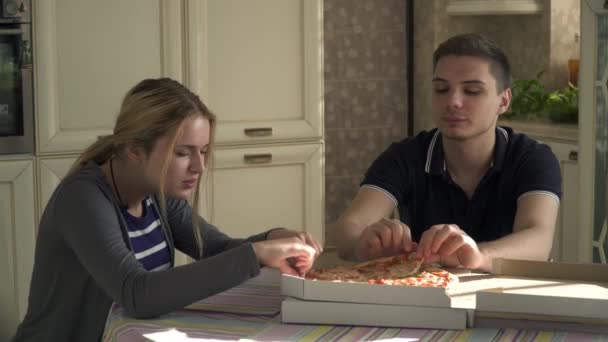 Pareja joven comiendo pizza en la cocina — Vídeos de Stock