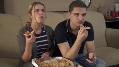 Kanepede oturan ve pizza yemek çekici genç çift
