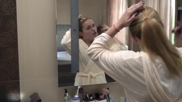 Hermosa rubia delante de un espejo en una bata — Vídeo de stock