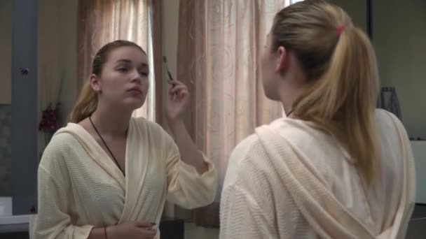 Beautiful young girl in front of a mirror in a dressing gown — Stock Video