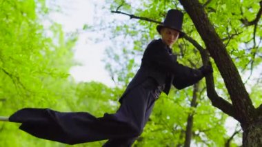 Genç adam kostüm parkta ağaç yakınındaki Stilts yürür