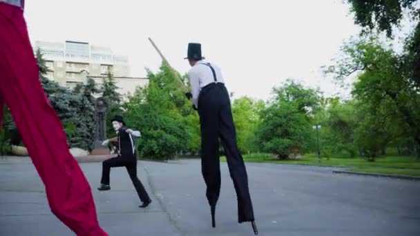 Deux échasses pourchassant mime dans la rue — Video