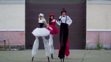 İki komik çift stilts binanın yakınındaki dans ediyor