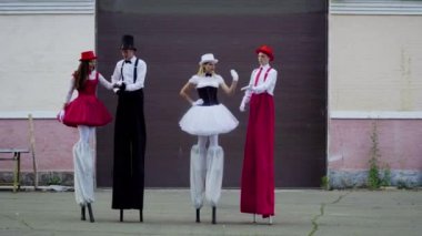 İki komik çift stilts binanın yakınındaki dans ediyor