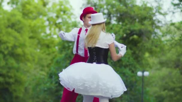 Смешная парочка комиков на ходулях танцует круто возле здания — стоковое видео