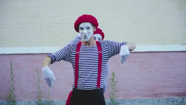 Two mimes in striped clothes make funny moves near building — Stock Video