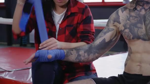Красивая брюнетка помогает свернуть руку боксера — стоковое видео