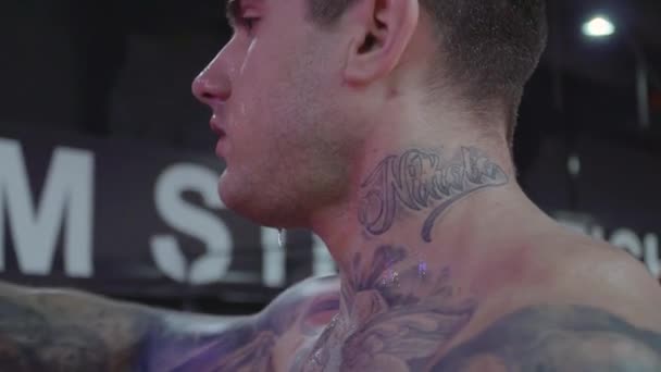 Knappe man met een tatoeage is drinkbaar water uit een fles — Stockvideo