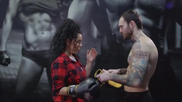 Красивый мужчина одевает боксерские перчатки для своей девушки — стоковое видео