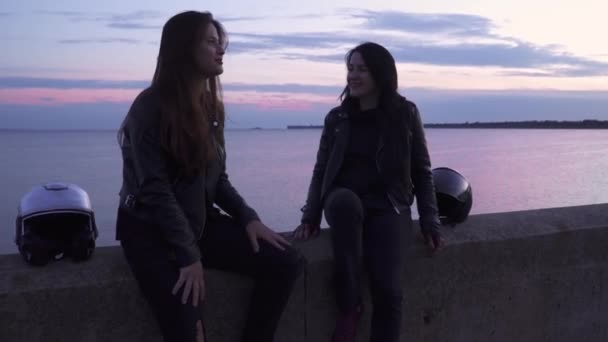 Deux belles filles motards parler et se détendre à fond de mer dans la soirée — Video