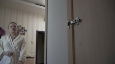 Genç Sarışın entres soyunma içine Oda ve uzakta belgili tanımlık sergen bir elbise alır