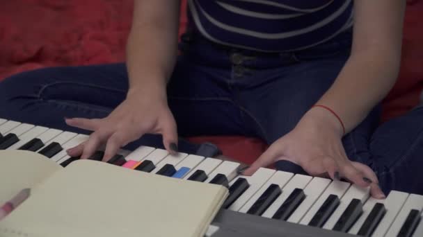 Young girl sitts on the couch and play on synthesizer — Stock Video