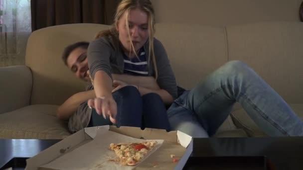 Aantrekkelijke jonge paar sitts op de Bank in de buurt van pizza — Stockvideo