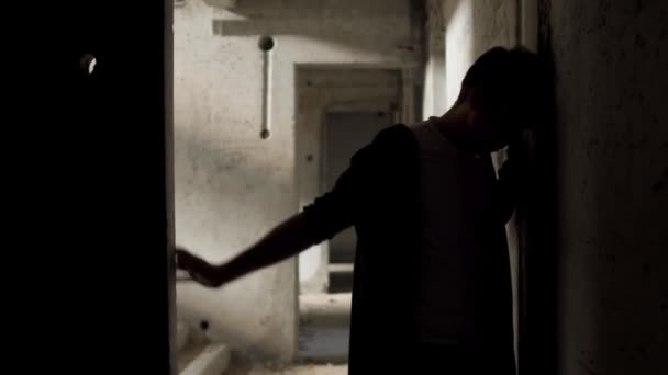 Yound hombre mal parecido se apoya contra las paredes en un edificio abandonado — Vídeos de Stock
