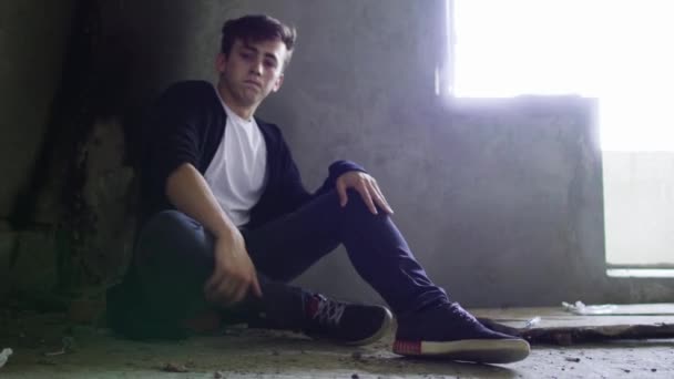 Jonge drugsverslaafde zittend op de vloer in het donker in een onafgewerkt huis — Stockvideo