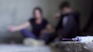 Arka plan kullanılan şırınganın katında oturan iki kişi