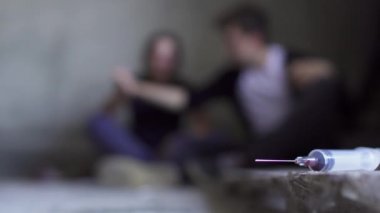 Arka plan kullanılan şırınganın katında oturan iki kişi