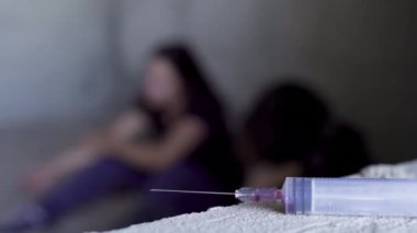 Arka plan kullanılan şırınganın katında oturan iki kişi