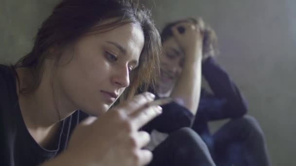 Giovane ragazzo e ragazza seduti sul pavimento dell'edificio grigio — Video Stock