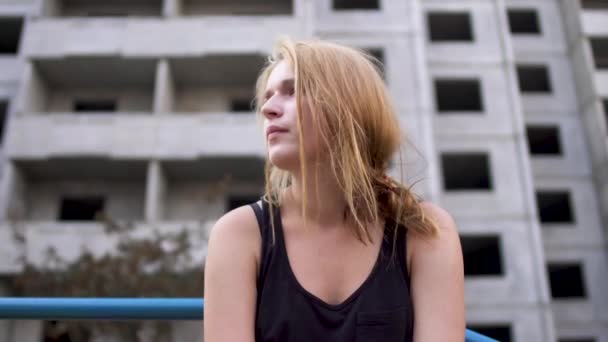 Дівчина сидить біля покинутої будівлі — стокове відео