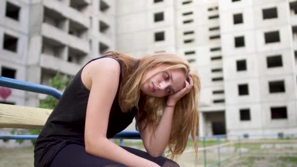 Нервова дівчина сидить біля високої будівлі — стокове відео