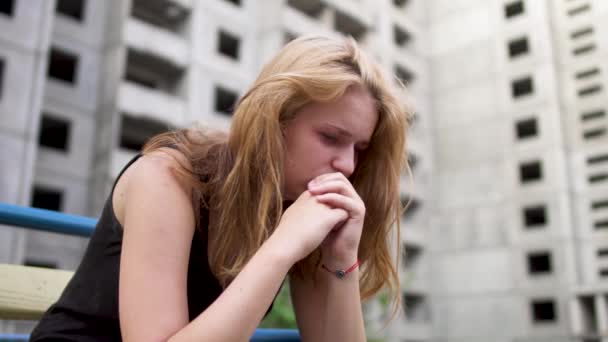 Нервная девушка сидит возле высокого здания — стоковое видео