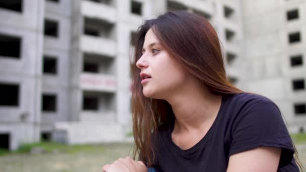 ブルネットの少女は高い建物の近くに座っている神経 — ストック動画