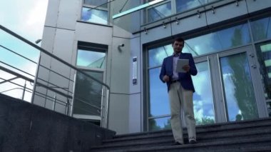 İşadamı onun elinde bir tablet ile iş merkezi'nden çıkar