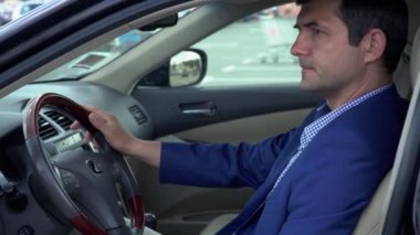 İşadamı bir ceket ve ekose gömlek arabada oturuyor