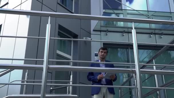 Бизнесмен стоит с табличкой на крыльце возле бизнес-центра — стоковое видео