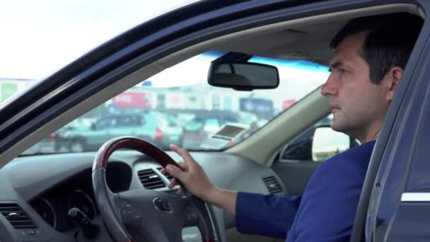 Empresário em uma jaqueta e camisa xadrez está sentado no carro — Vídeo de Stock