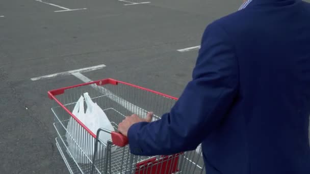 Schöner Mann trägt einen Einkaufswagen auf dem Parkplatz — Stockvideo