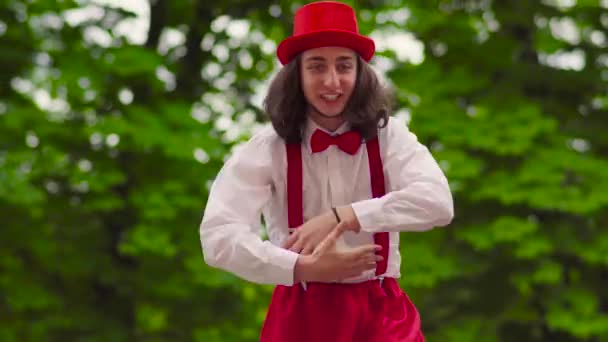 Grappige jonge mime loopt op stelten en jongleren in het park — Stockvideo