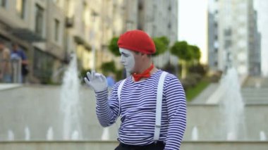 Kırmızı bere içinde komik MIME gesticulate çeşmeler arka plan ellere