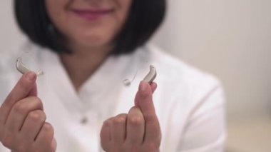 Tıbbi bir klinik çalışanı bir işitme cihazı gösterir