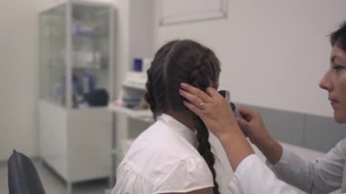 Hemşire bir kız kulak inceliyor