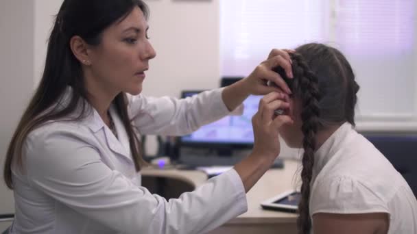 Médico ajuda uma menina com um aparelho auditivo — Vídeo de Stock