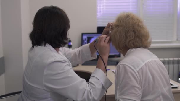 Médico profesional examina el oído de una mujer adulta — Vídeos de Stock