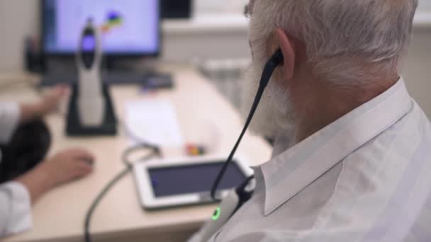 Homem adulto com barba cinza passa no teste para audição — Vídeo de Stock