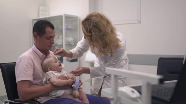 Люблячий батько тримає свою маленьку дочку на руках у лікарні — стокове відео